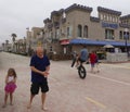 A Biker Wheelies Past a Grandfather and Granddaughter on Ocean F Royalty Free Stock Photo