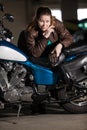 Biker woman with a heavy build standing near her motorcycle, leaning the seat, looking at camera Royalty Free Stock Photo