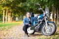 Biker woman with white helmet and jeans outfit portrait, sitting close to motorcycle, copy space Royalty Free Stock Photo