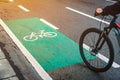 Bikers crossing a bike path for cyclist beside the main traffic road in green color