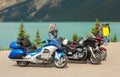 Bikers pausing to admire the view of a turquoise-colored lake in northern canada