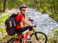 Bikes cycling girl with big rucksack cycling fording throught water into park. Royalty Free Stock Photo