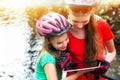 Bikes cycling girl. Children rides bicycle. Bicyclist watch tablet computer.