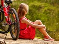 Bikes cycling girl into park. Girl sits leaning on bicycle on shore. Royalty Free Stock Photo