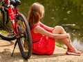 Bikes cycling girl into park. Girl sits leaning on bicycle on shore. Royalty Free Stock Photo