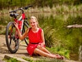 Bikes cycling girl sits near bicycle on shore into park.