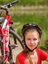 Bikes cycling girl wearing helmet have a rest sitting under tree. Royalty Free Stock Photo