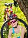 Bikes cycling girl wearing helmet have a rest sitting under tree. Royalty Free Stock Photo