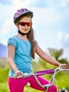 Bikes cycling girl wearing helmet rides bicycle aganist blue sky. Royalty Free Stock Photo