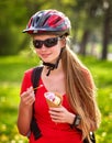 Bikes cycling girls with rucksack cycling eating ice cream cone in summer park. Royalty Free Stock Photo