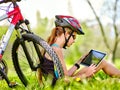 Bikes girl wearing helmet sitting near bicycle watch pc tablet.