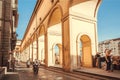 Bikes and people on street with historical arches of the ancient Tuscany city