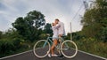 Biking road trip. Love couple on blue bike in white clothes on forest road. Just married woman and man kiss, hugs, stand Royalty Free Stock Photo