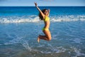 Bikini girl jumping in Caribbean sunset beach