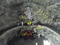 Bila, Czech - 10 19 2014: Old statue of Virgin Mary of Lurds inside a cave chapel surrounded by artificial and live flowers and