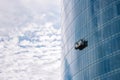 Skyscraper with washing gondola on sky background. Modern urban buildings concept. Climbing window cleaner in skyscraper.