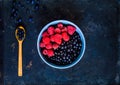 Bilberry and raspberries in blue bowl, the concept of organic berries bowl on vintage rusty metal background.