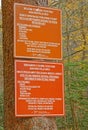 bilingual sign in English and Spanish attached to tree trunk explaining park rules
