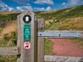 Bilingual signage on a wooden gate  in Welsh and English giving information to walkers on the Pembrokeshire Coast Path in Wales Royalty Free Stock Photo