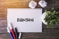 Bilingual word with Notepad and green plant on wooden background Royalty Free Stock Photo