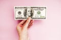 Bill in hand on a pink background. 100 dollars. Money Royalty Free Stock Photo