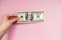 Bill in hand on a pink background. 100 dollars. Money Royalty Free Stock Photo