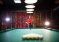 Billiard club. A woman with red hair standing by the table holding a cue Royalty Free Stock Photo