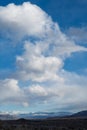 Billowy white clouds in blue sky over snowy mountain shrouded in clouds Royalty Free Stock Photo