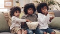 Binging buddies. three adorable little boys eating popcorn and watching movies together at home. Royalty Free Stock Photo