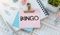 Bingo text on a pink paper sticker lying on a wooden table