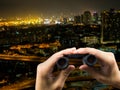 Binocular on hand holding and cityscape at night