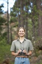 Binocular, nature and portrait of happy woman hiking in forest journey, jungle adventure and travel or outdoor explore