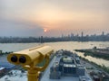 A binocular pointing the sunset behind Manhattan skyline from a rooftop