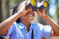 Binocular, search and boy child in a forest for hiking, sightseeing or discovery. Lens, equipment and happy African kid