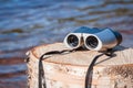 Binoculars lie on stump on seashore. Concept of new discovery and water tourism
