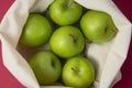 Bio fruit - green apples in white tote canvas fabric. Eco bag cloth shopping sack on colrful red background . Zero waste concept Royalty Free Stock Photo