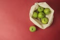 Bio fruit - green apples in white tote canvas fabric. Eco bag cloth shopping sack on colrful red background . Zero waste concept. Royalty Free Stock Photo