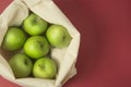 Bio fruit - green apples in white tote canvas fabric. Eco bag cloth shopping sack on colrful red background . Zero waste concept. Royalty Free Stock Photo