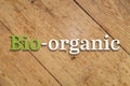 `Bio-organic` white-green text on a wooden background.