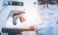 Biochemical research scientist working with microscope for coronavirus, laboratory glassware containing chemical liquid for design Royalty Free Stock Photo
