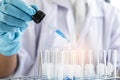 Biochemistry laboratory research, Scientist or medical in lab coat holding test tube with using reagent with drop of color liquid