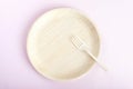 Biodegradable bamboo plate with fork on light pink background