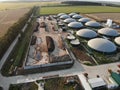 Biogas complex on nature landscape. Agricultural plant for biomass production on green field. Modern storage for