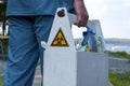 Biohazard sign on the box with samples of water from the lake in the hands of an employee