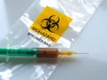 Biohazard specimen bag with a syringe and brown liquid