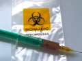 Biohazard specimen bag with a syringe and brown liquid