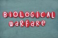 Biological Warfare text composed with red stone letters over green sand Royalty Free Stock Photo