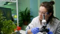 Biologist scientist looking at green leaf sample under microscope