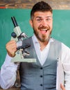 Biology or chemistry concept. Happy teacher with computer and microscope. Excited tutor in classroom.