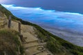 Long exposure of Beautiful Blue Bioluminescence at Black`s Beach in San Diego. Trail and wooden stairs in the foreground.